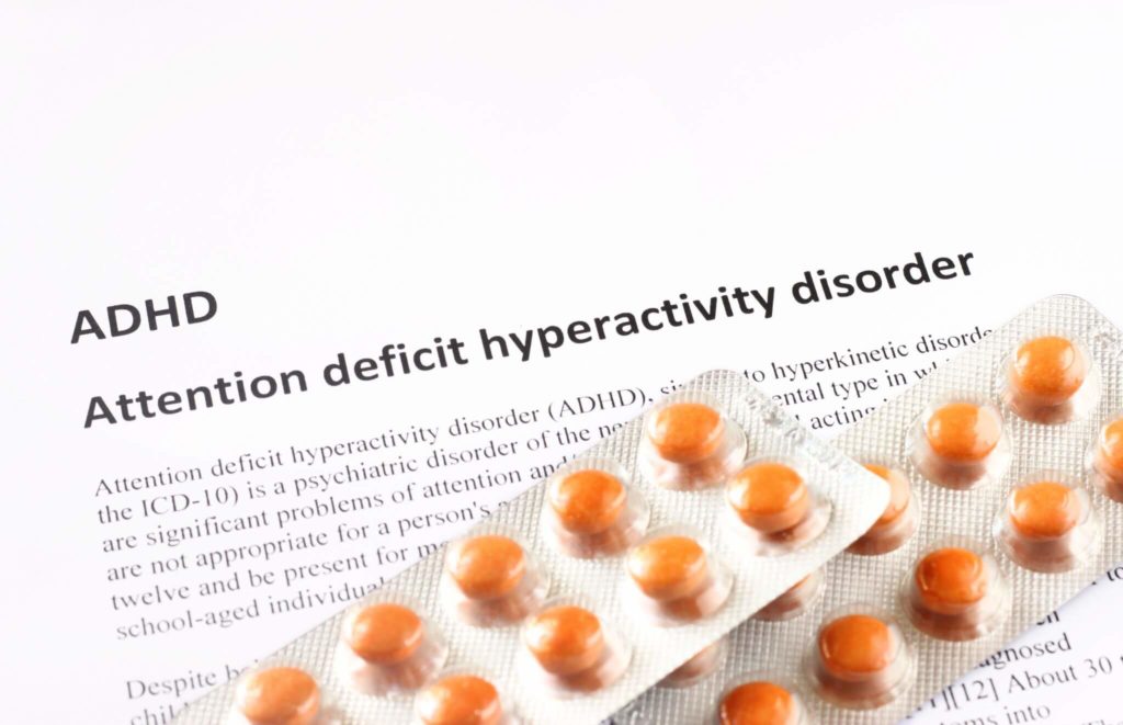 ADHD, Attention deficit hyperactivity disorder written on piece of paper with medication on it